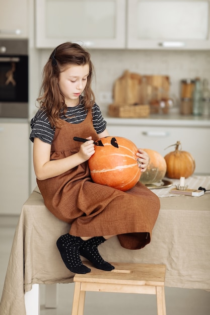 Het meisje schildert een pompoen voor Halloween-voorbereiding voor Halloween