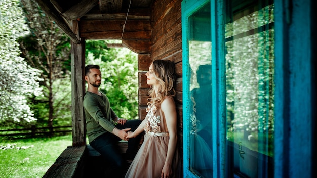 Het meisje sluit haar ogen en houdt de man vast op de veranda van het oude Hutsul-huis. het concept van een liefdesverhaal. rond het groen en de lente