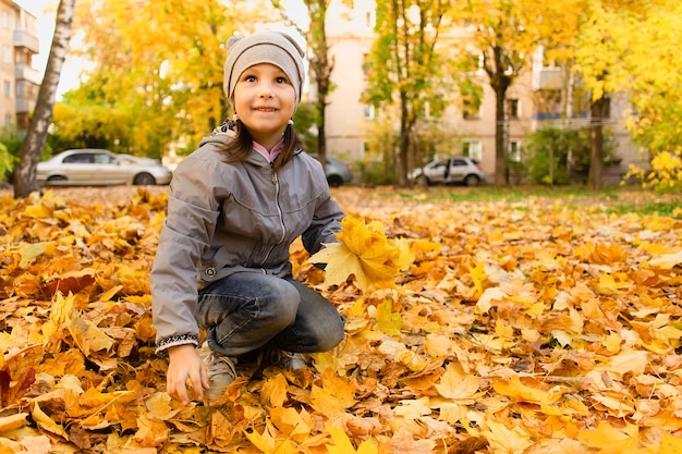 Het meisje speelt in herfstbladeren