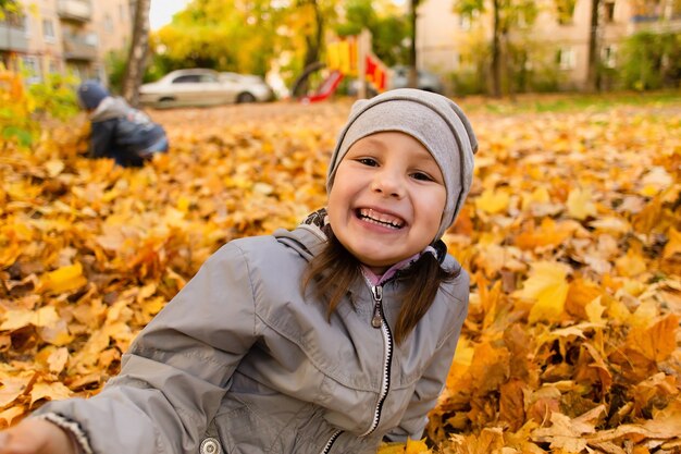 Het meisje speelt in herfstbladeren