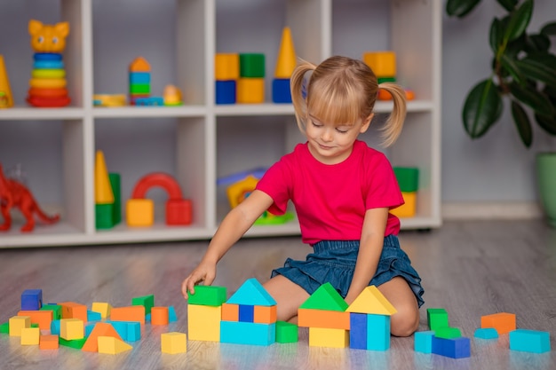 Het meisje speelt thuis met speelgoed, op de kleuterschool of in de kinderkamer.