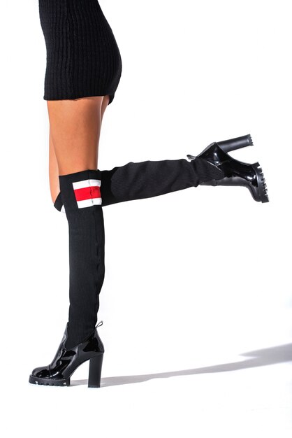 Foto het meisje staat in zwarte jute laarzen op de voeten van een model op een witte achtergrond