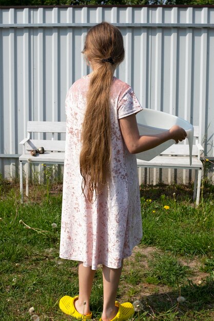 Foto het meisje staat met haar rug en houdt een plastic bakje in haar handen