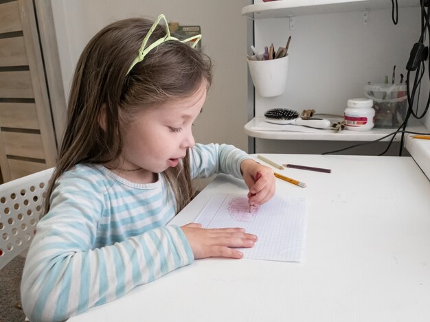 Het meisje trekt met kleurpotloden met haar linkerhand