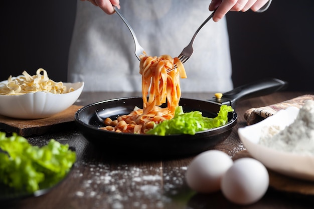 Het meisje trekt pasta uit de pan met een vork