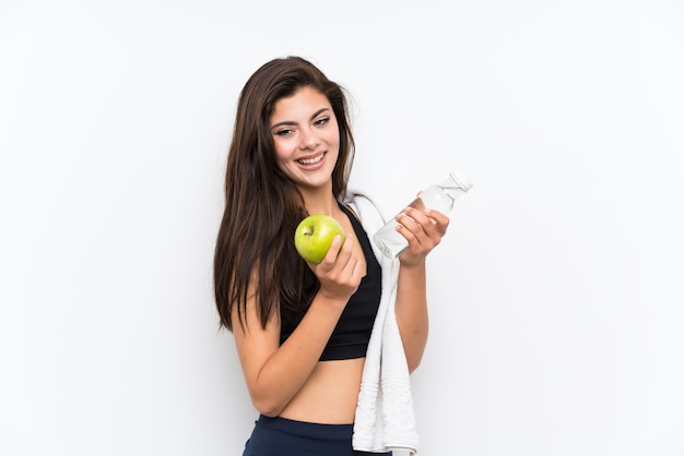 Het meisje van de tienersport over geïsoleerde witte muur met een appel en een fles water