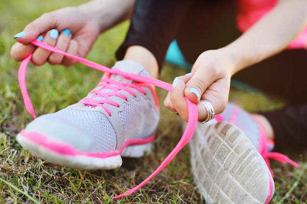 Het meisje verbindt schoenveters op tennisschoenen alvorens te lopen of vóór geschiktheidstraining op van van aard