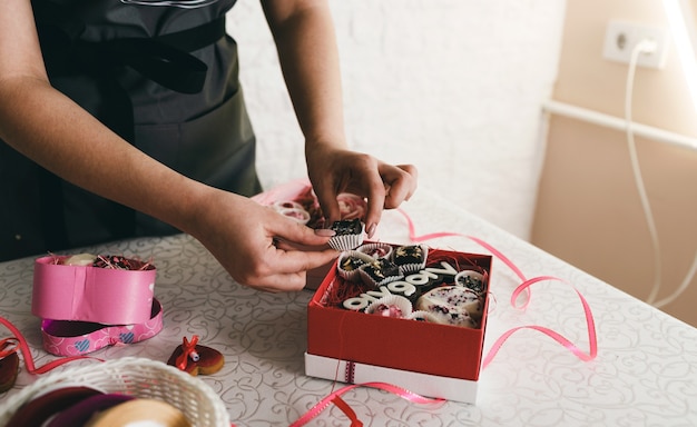 Het meisje verpakt de taarten in kleurrijke geschenkdozen.