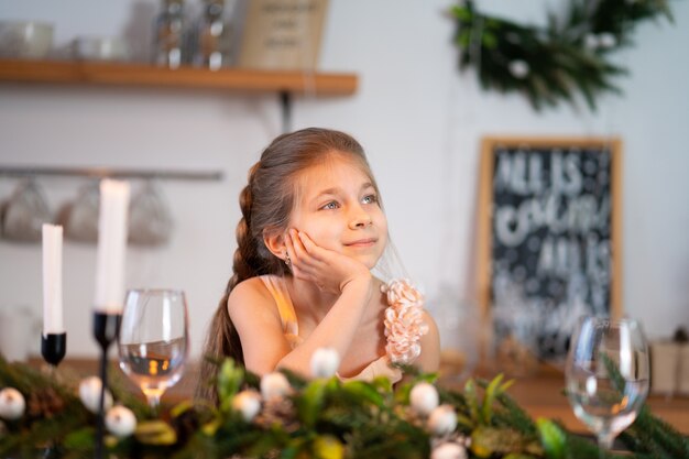 Het meisje verveelt zich tijdens de kerstnacht aan de feesttafel.