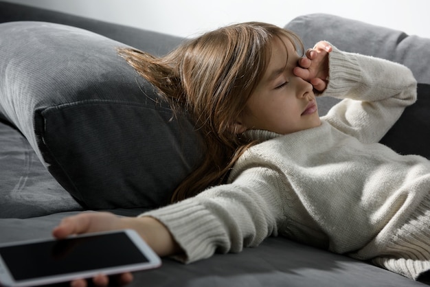 Het meisje viel in slaap met een smartphone op de bank.