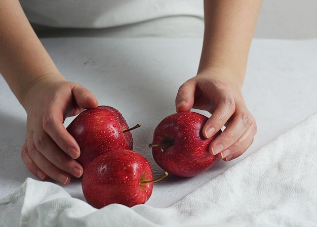 Het meisje waste en zette de rode appels op tafel. Vlakbij ligt een witte handdoek