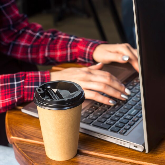 Het meisje werkt achter een laptop aan een tafel in een café naast een kop koffie