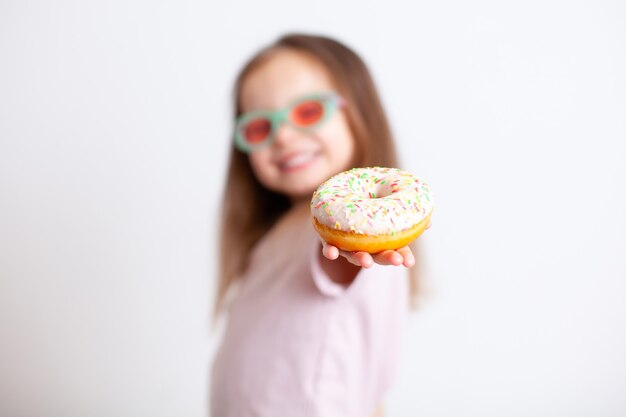 Het meisje wijst met een ontevreden gezicht met haar vinger naar de donut Emoties Schadelijk voedsel