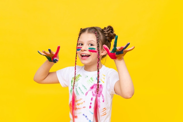 Het meisje wijst naar boven Een kind met verf op een gele geïsoleerde achtergrond Tekencursussen voor kinderen Ontwikkeling van de creativiteit van kinderen