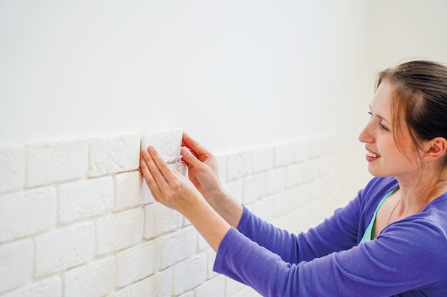 Het meisje zet decoratieve baksteen op de muur op