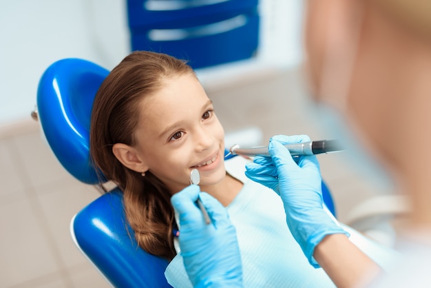 Het meisje zit als tandvoorzitter bij de ontvangst van een tandarts.