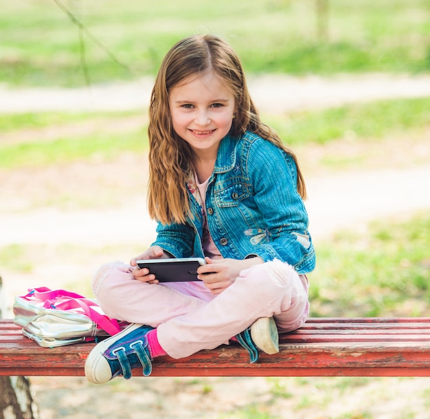 Het meisje zit met haar telefoon in park