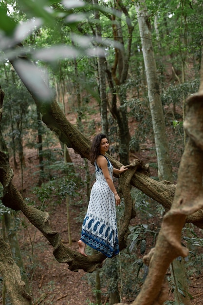 Foto het meisje zit op een enorme liaanboomtak in de jungle.