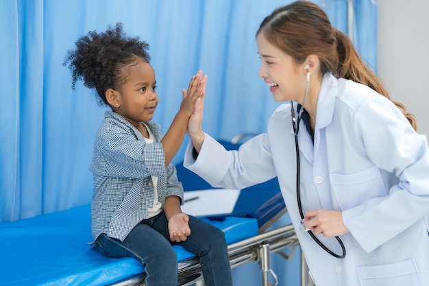 Het meisje zit op het bed van de patiënt voor de dokter