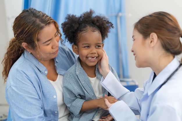 Het meisje zit op het bed van de patiënt voor de dokter