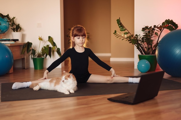 Het meisje zit op touw op haar laptop online training in sport en stretching