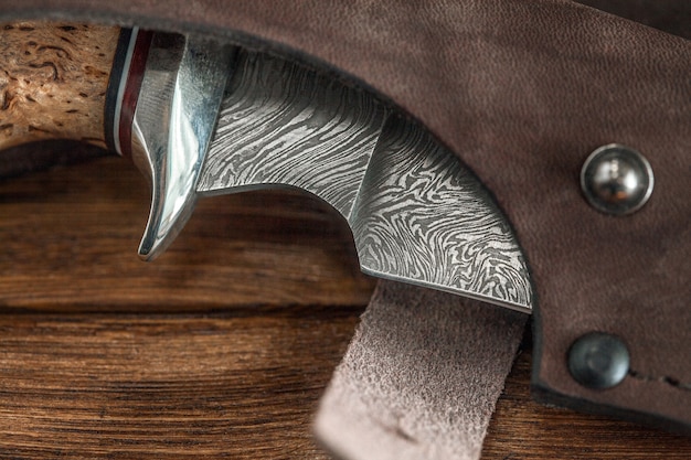 Het mes van het de jachtdamascus staal met de hand gemaakt op een houten muur, close-up