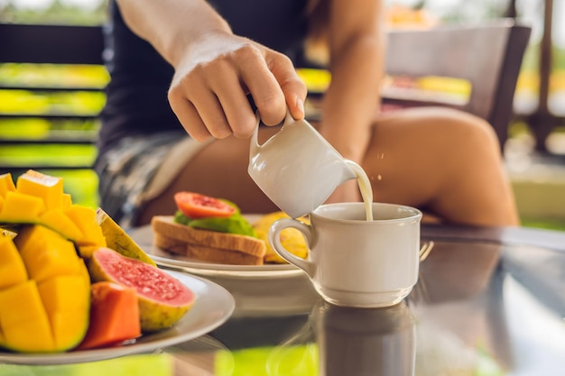 Het moment dat melk in koffie wordt gegoten. Vrouw gieten room in koffie.