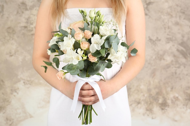 Het mooie boeket van de bruidholding met fresia'sbloemen op lichte achtergrond
