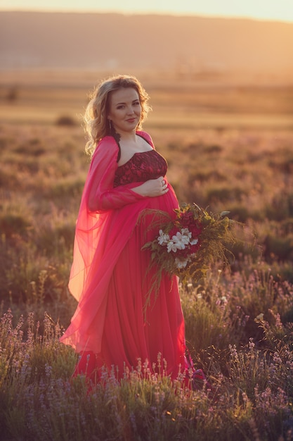 Het mooie de zwangere vrouw van de Provence ontspannen op lavendelgebied het letten op op de mand van de zonsondergangholding met lavandabloemen. Serie. verleidelijk meisje met paarse lavendel. blonde dame in bloesem veld