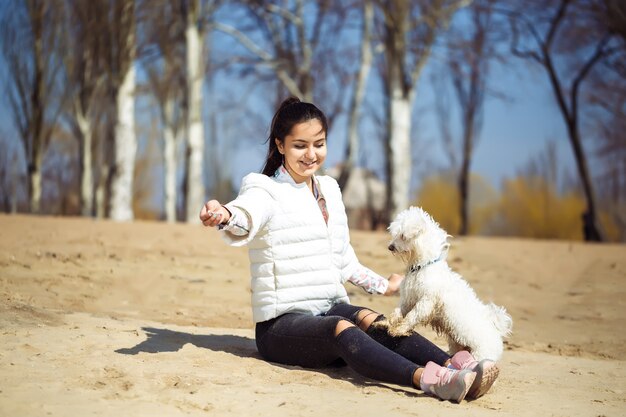 Het mooie Europese jonge vrouw spelen met hond in openlucht in het park. zonnige dag. zandstrand.