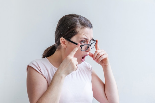 Het mooie gelukkige meisje glimlachen. Schoonheid eenvoudig portret jonge lachende brunette vrouw in bril geïsoleerd op een witte achtergrond.