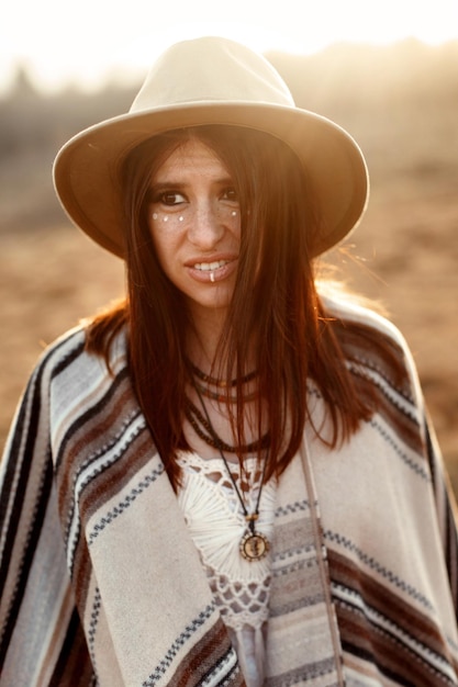 Foto het mooie hipster portret van de bohovrouw met hoed en poncho bij zonsondergang in de bergen ziet er grappig uit