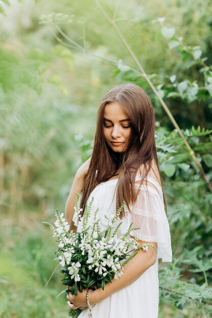 Het mooie jonge donkerbruine boeket van de vrouwenholding van wildflowers in de zomer