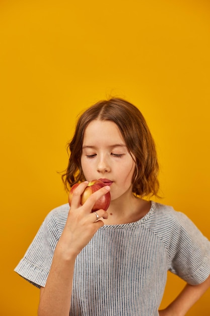 Het mooie kind van het tienermeisje eet bijt een verse rode appel