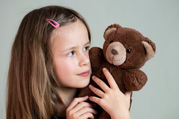 Het mooie kindmeisje spelen met haar teddybeerstuk speelgoed.