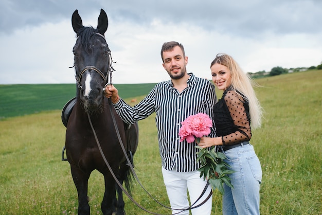 Het mooie paar verliefd omarmen in de buurt van paard