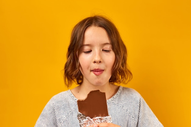 Het mooie tienermeisje eet bijt een chocoladereep