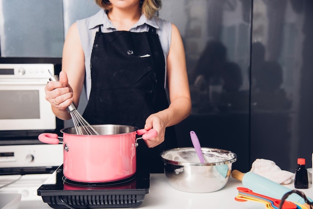 Het mooie vrouwen koken zwaait deeg in komhandboek