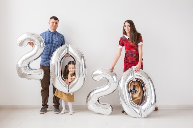 Het nieuwe 2020-jaar komt eraan-concept - Gelukkige familie met hond houdt binnenshuis zilverkleurige cijfers vast.