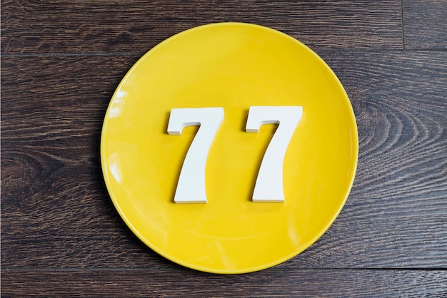 Foto het nummer zevenenzeventig op het gele bord