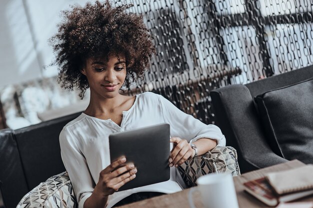 het onderzoeken van haar nieuwe digitale tablet. mooie jonge afrikaanse vrouw in slimme vrijetijdskleding