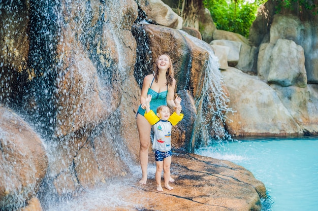 Het ontspannen van de moeder en van de zoon onder een waterval in aquapark