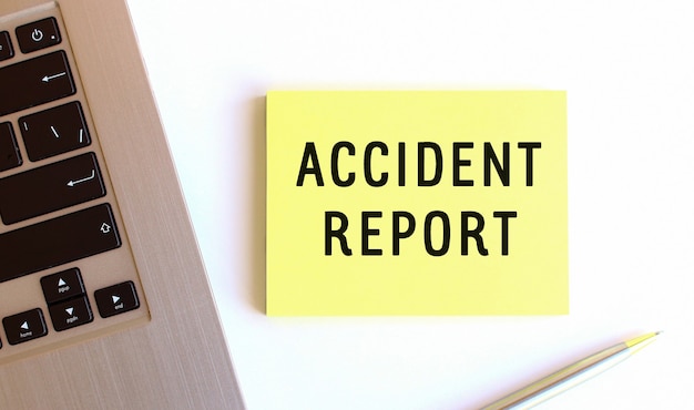 Het opschrift ongevallenrapport op de gele plaknotities bij de laptop