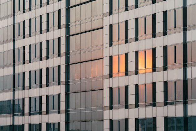 Het oranje licht van de zonsondergang dat op glas en bekledingsvoorgevel wordt weerspiegeld in de avond.