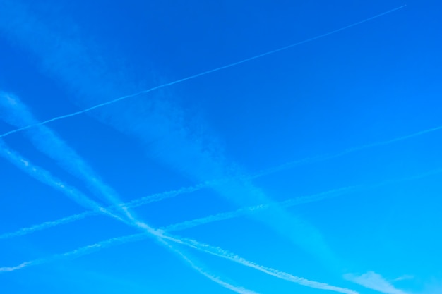 Het oversteken van vliegtuigsporen in de blauwe lucht, kan als achtergrond worden gebruikt