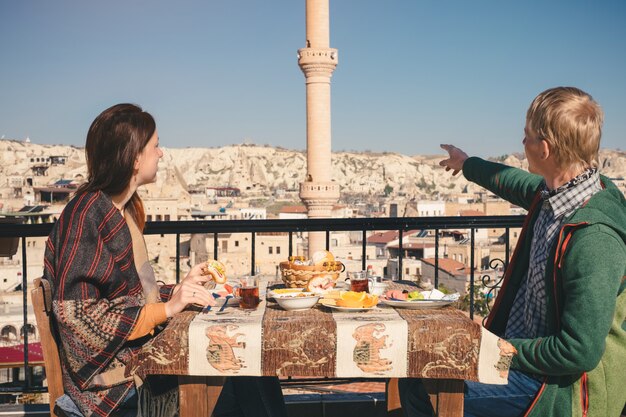 Het paar eet traditioneel turks ontbijt op dak met uitzicht op de stad