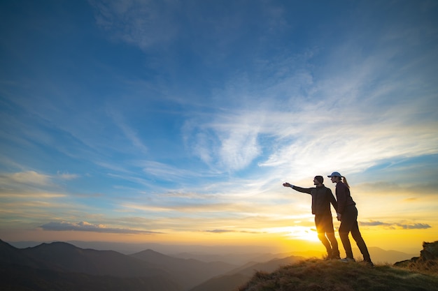 Het paar gebaren op de berg met een schilderachtige zonsondergang op de achtergrond