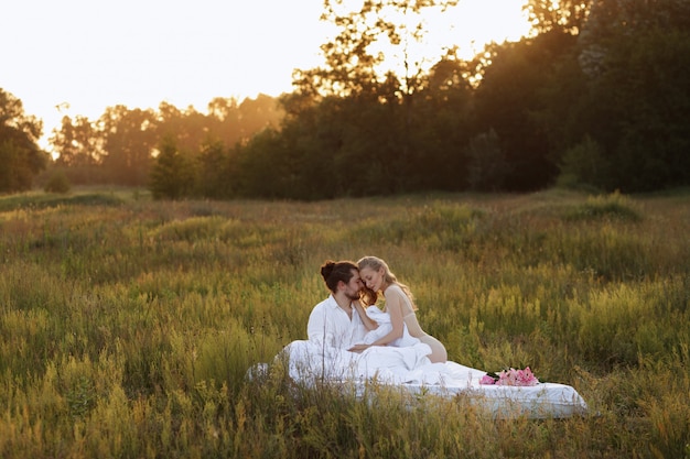 Het paar is gelukkig in de natuur in bed in de ochtend bij zonsopgang. reclame voor beddengoed