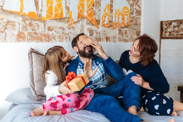 Het paar ontspande thuis in bed met weinig dochter die een verrassing met giften maken