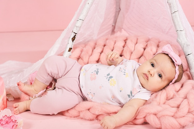 Het pasgeboren babymeisje in roze lint ligt bij een bed